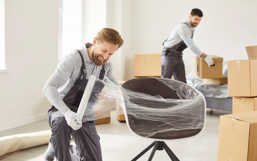 Umzugsteam verpackt einen Designerstuhl mit Schutzfolie