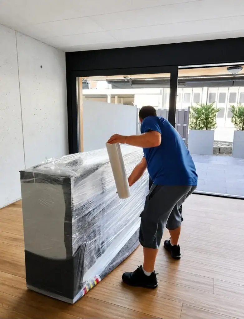 Schrank wird vor dem Transport in Folie eingewickelt