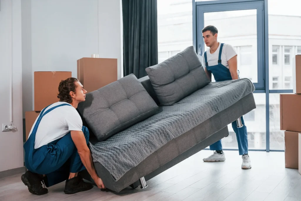 Zwei Mitarbeiter von Optimal Umzug tragen ein Sofa bei einer Wohnungsräumung